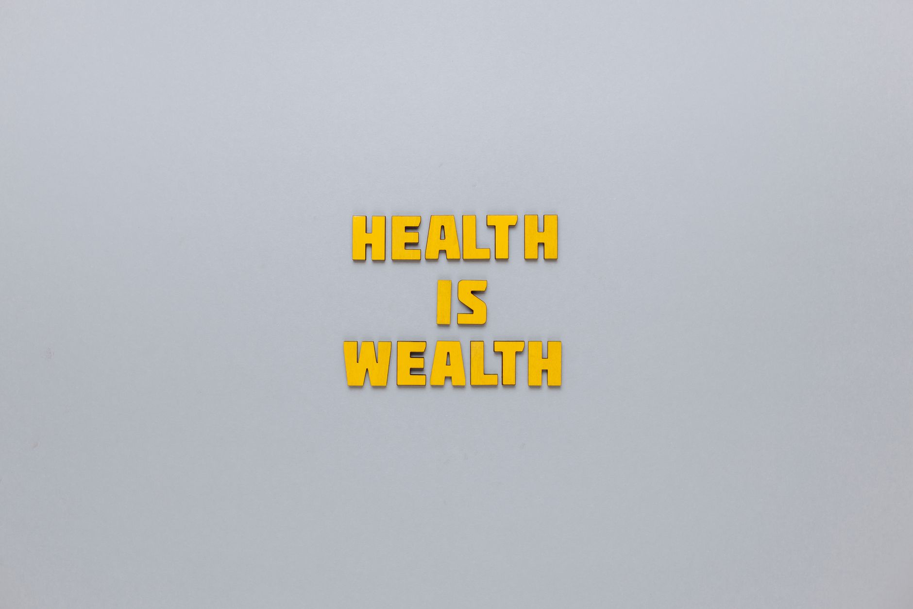 Inspirational phrase 'Health is Wealth' in bold yellow letters on a neutral gray background. — Balancing Cost and Quality in