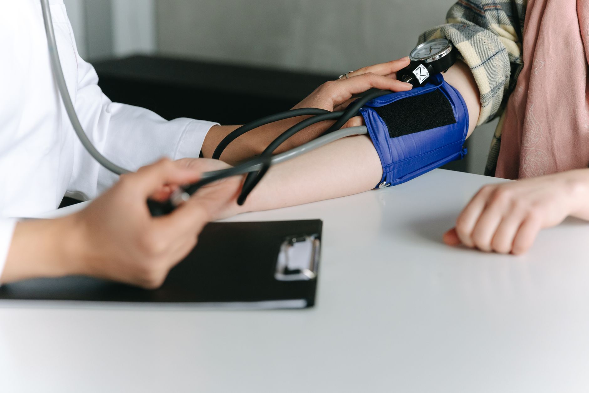 A healthcare worker uses a sphygmomanometer to check a patient's blood pressure in a medical office. — Discover Why Many Seni