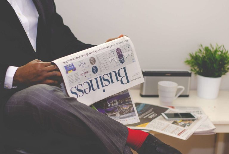 Businessman reading a financial newspaper at a desk, highlighting finance and commerce theme. — Experience Stress-Free Nang D