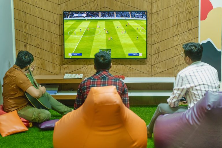 Three friends relaxing and playing a soccer video game indoors on a comfortable game night. — How MPO2121 Combines Classic an