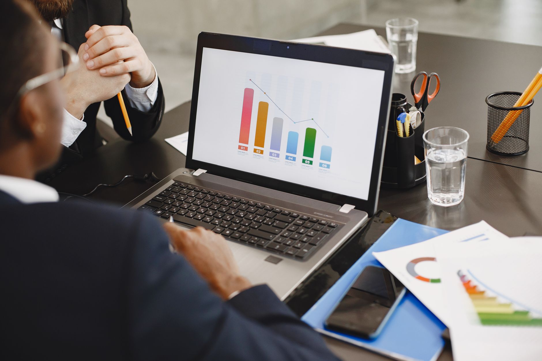 Two professionals analyzing a business graph on a laptop during a meeting. — Record Every Detail with Ease Using a General Le