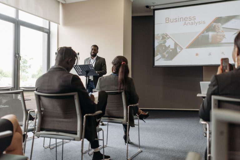 A business professional delivering a presentation in a conference room with diverse attendees. — Sex Toys for Beginners: What